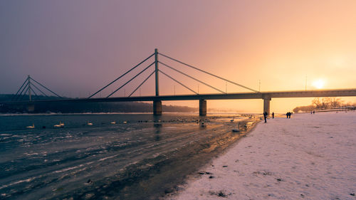 Suspension bridge over sea during sunset