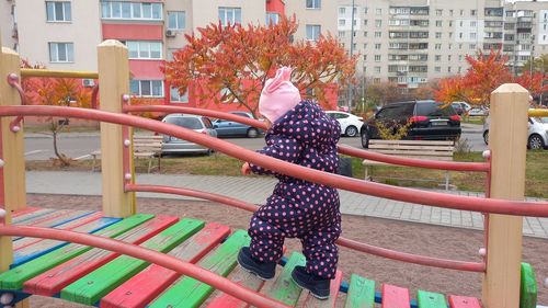 Rear view of woman standing with umbrella against buildings