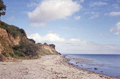 View of calm beach against cloudy sky