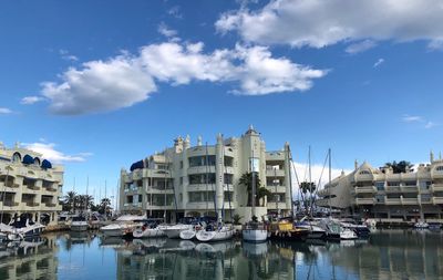 Boats moored at harbor by buildings in city