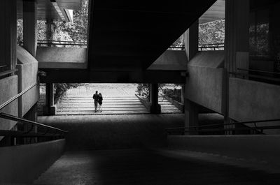 Rear view of couple walking on staircase in building