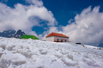 House on snow covered mountain against sky