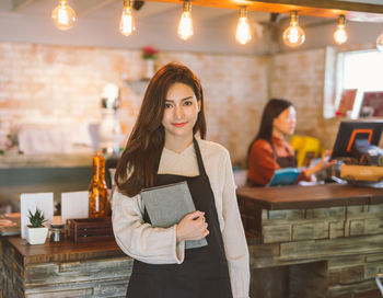 Portrait of young woman using phone while standing on table
