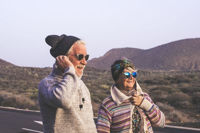 Portrait of friends against mountain range against clear sky