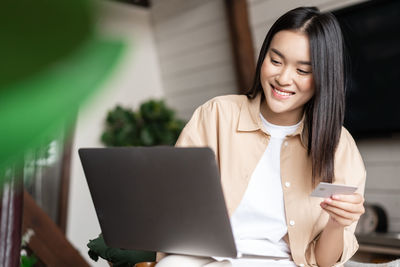 Young woman using laptop while sitting on table