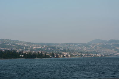 Scenic view of sea and buildings against clear sky