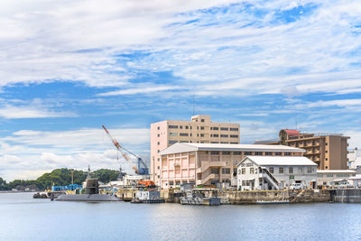 Buildings by harbor against sky in city