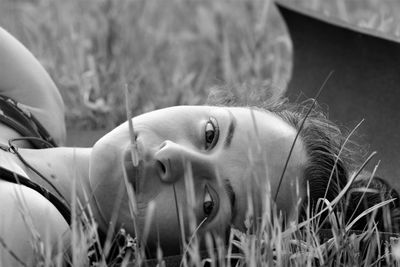 Close-up portrait of young woman lying on grassy land