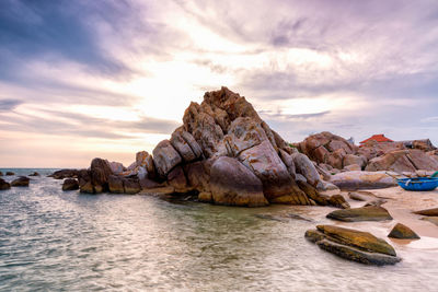 Rock formation by sea against sky