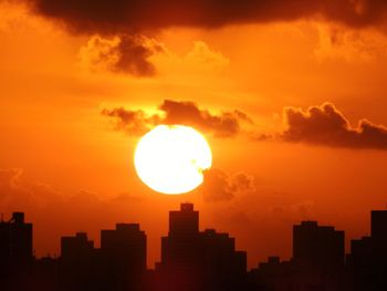 Silhouette buildings against orange sky during sunset