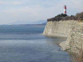 Lighthouse by sea against sky