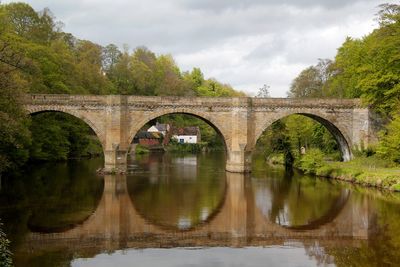 Arch bridge over river against sky