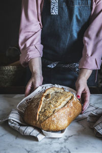 Close-up of a woman holding a loaf of bread with her hands