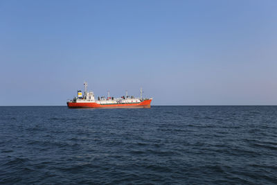 Boat sailing in sea against clear sky