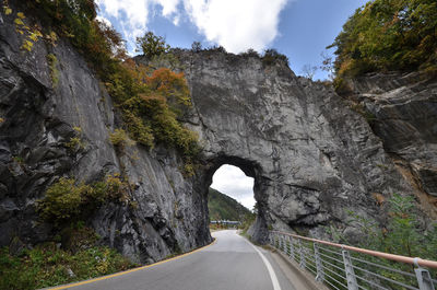 Road amidst rocks and trees against sky