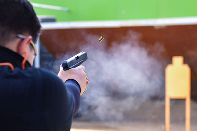 Rear view of man shooting target with handgun