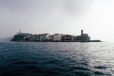 Sea by cityscape against sky