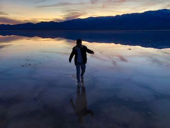 Full length of man on beach against sky during sunset