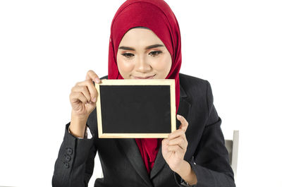 Portrait of woman holding camera over white background