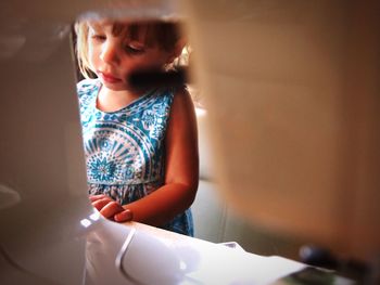 Girl standing by sewing machine at home