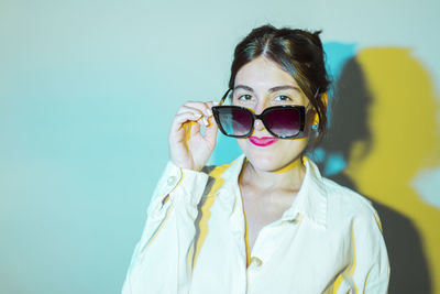 Portrait of young woman wearing sunglasses against sky