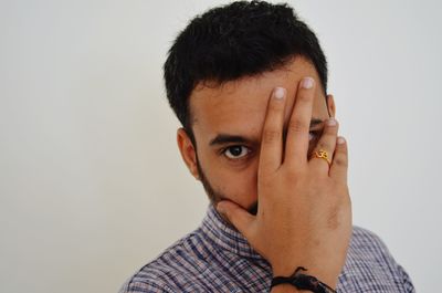 Close-up portrait of man covering face against white background