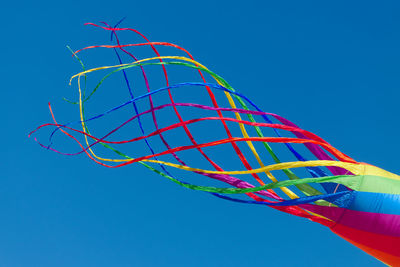 Low angle view of multi colored umbrella against clear blue sky