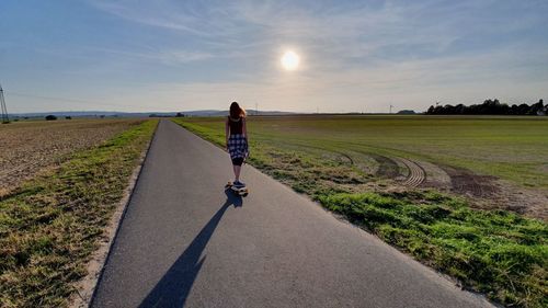 Rear view of woman riding motorcycle on road