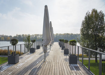 Wooden footbridge by lake against sky