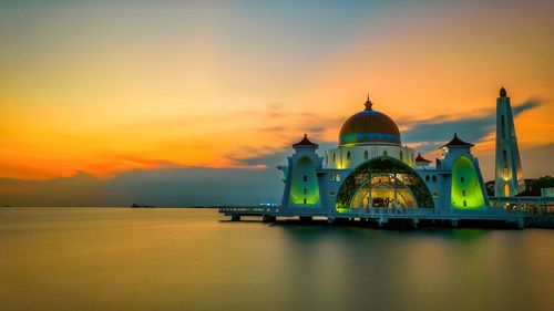 Temple by building against sky during sunset