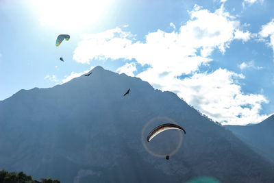 Person paragliding over mountain against sky