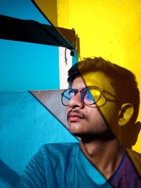 Portrait of young man wearing sunglasses against wall