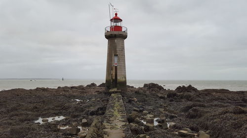 Lighthouse by sea against sky