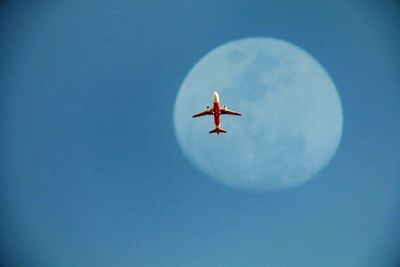 Low angle view of airplane flying against clear blue sky