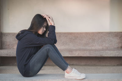 Midsection of woman sitting on staircase against wall