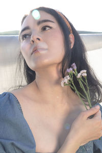 Pretty ethnic woman outside holding flowers with unique lighting