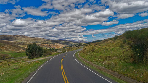 Road leading towards mountains against sky