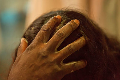 Cropped hand of woman applying oil in 
hair