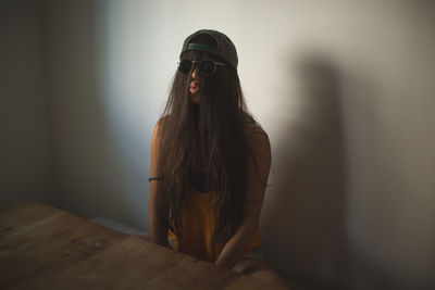 Funny woman with hair covering face puckering lips while sitting by table