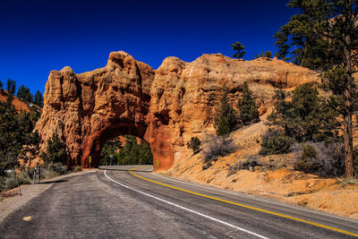 Road leading towards rock against blue sky