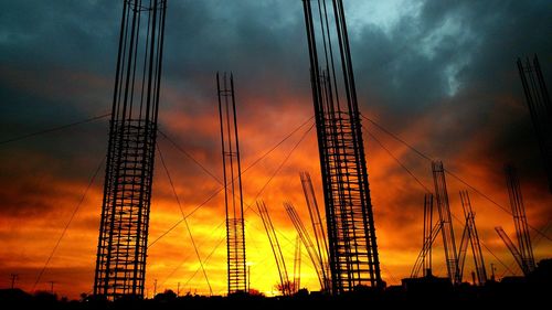 Low angle view of silhouette metal rods at construction site against cloudy sky during sunset