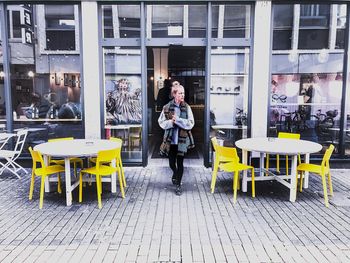 Full length portrait of young woman standing in cafe