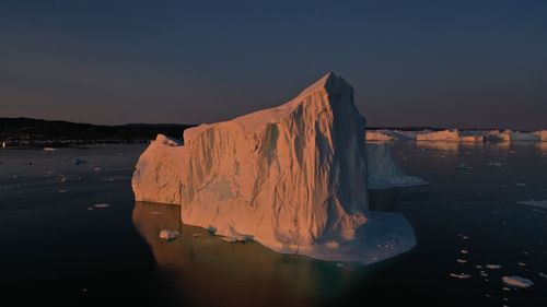 Scenic view of sea by city against sky during sunset