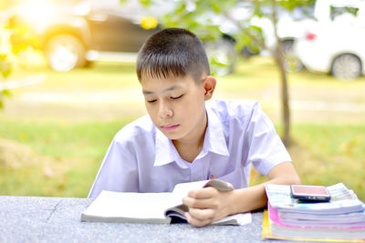 Boy reading book while sitting at park