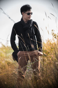 Young man standing on field against sky