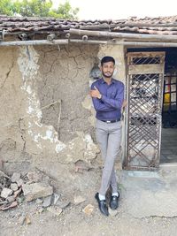 Portrait of young man standing against wall