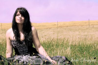 Beautiful young woman sitting on field