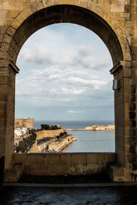 Arch bridge over sea against buildings