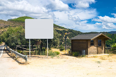 Information sign on field by houses against sky