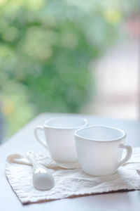 Close-up of spoon with coffee cups on napkin at table